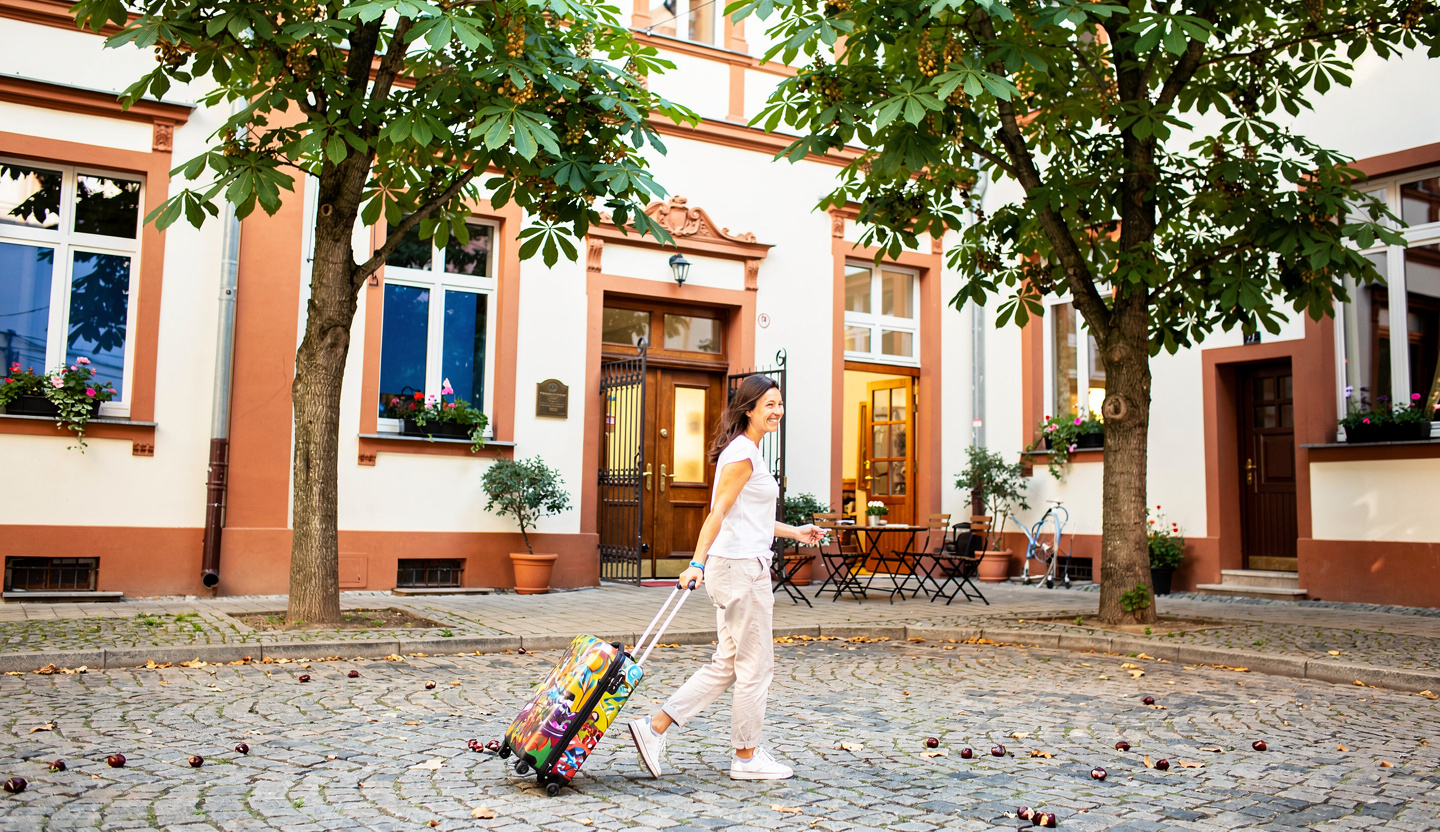 Frau mit Koffer in einem Krakauer Innenhof.