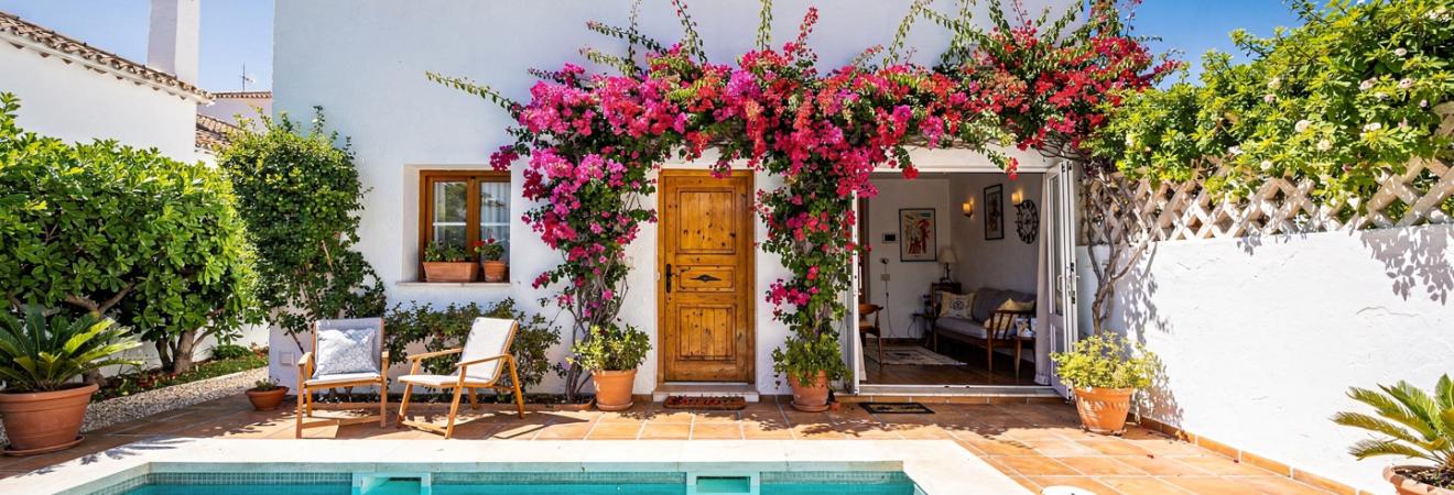 Weißes andalusisches Ferienhaus mit Bougainvillea und kleinem Pool.