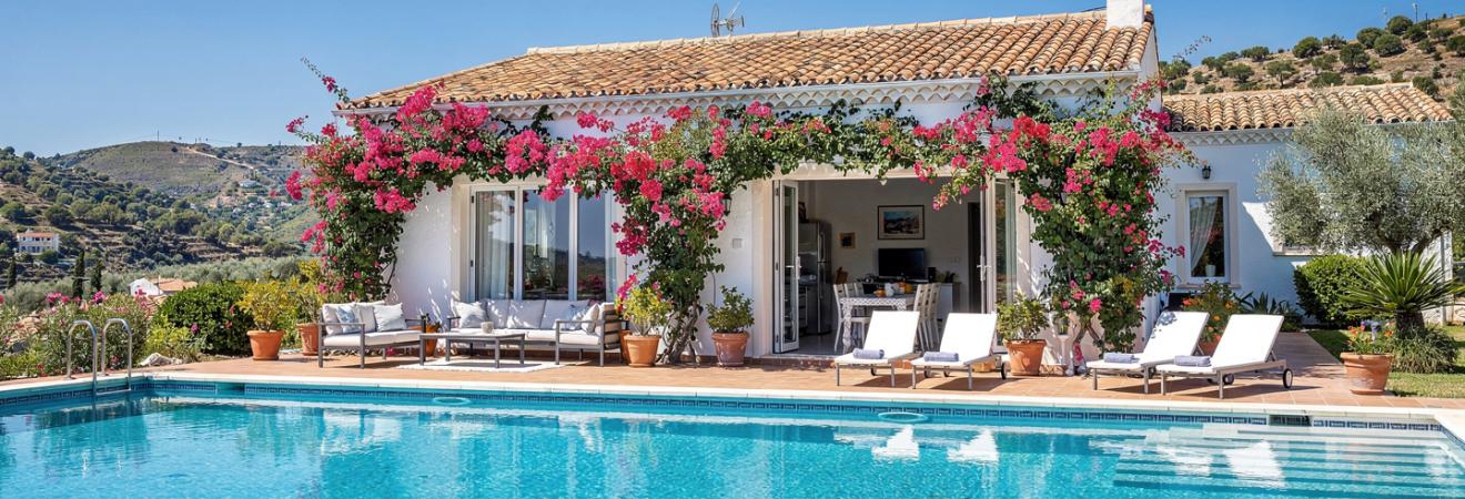 Mediterrane Ferienvilla mit Pool und Oleander unter blauem Himmel.
