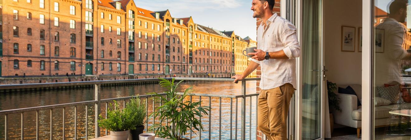 Mann mit Kaffee auf einer Terrasse an einem Hamburger Kanal.